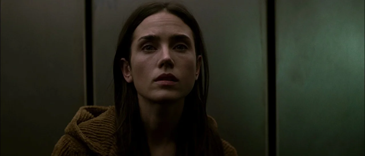 Dark Water (2005) movie still: closeup — The interior of an elevator with brushed metallic green wall panels. A woman stands in the center looking…