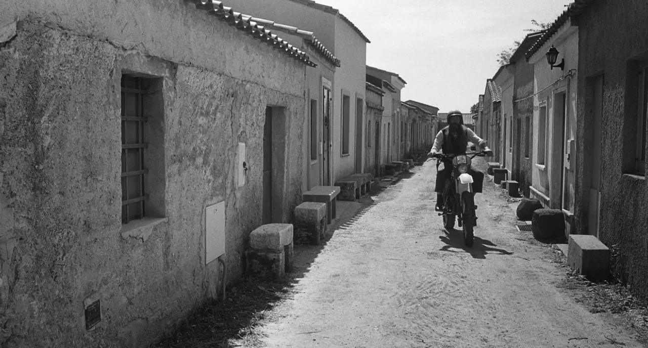 The Legend Of Kaspar Hauser (2012) movie still: wide — An alleyway lined with textured stucco buildings and stone blocks sitting near the path. A…