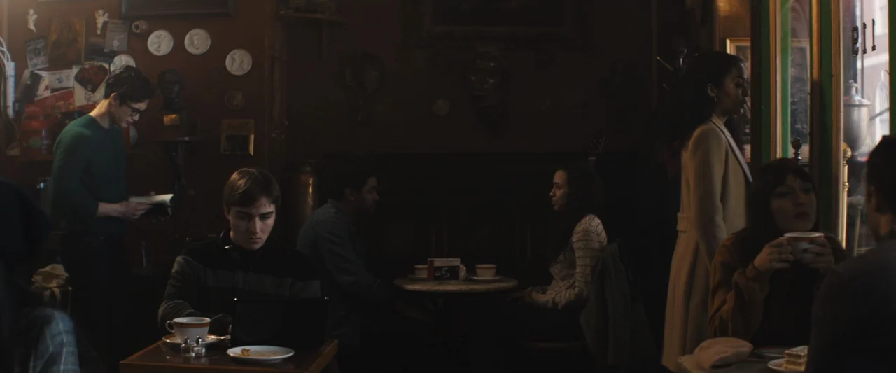 The Sun Is Also a Star (2019) movie still: medium — A dimly lit cafe interior features dark wooden walls decorated with small plates and plaques.…
