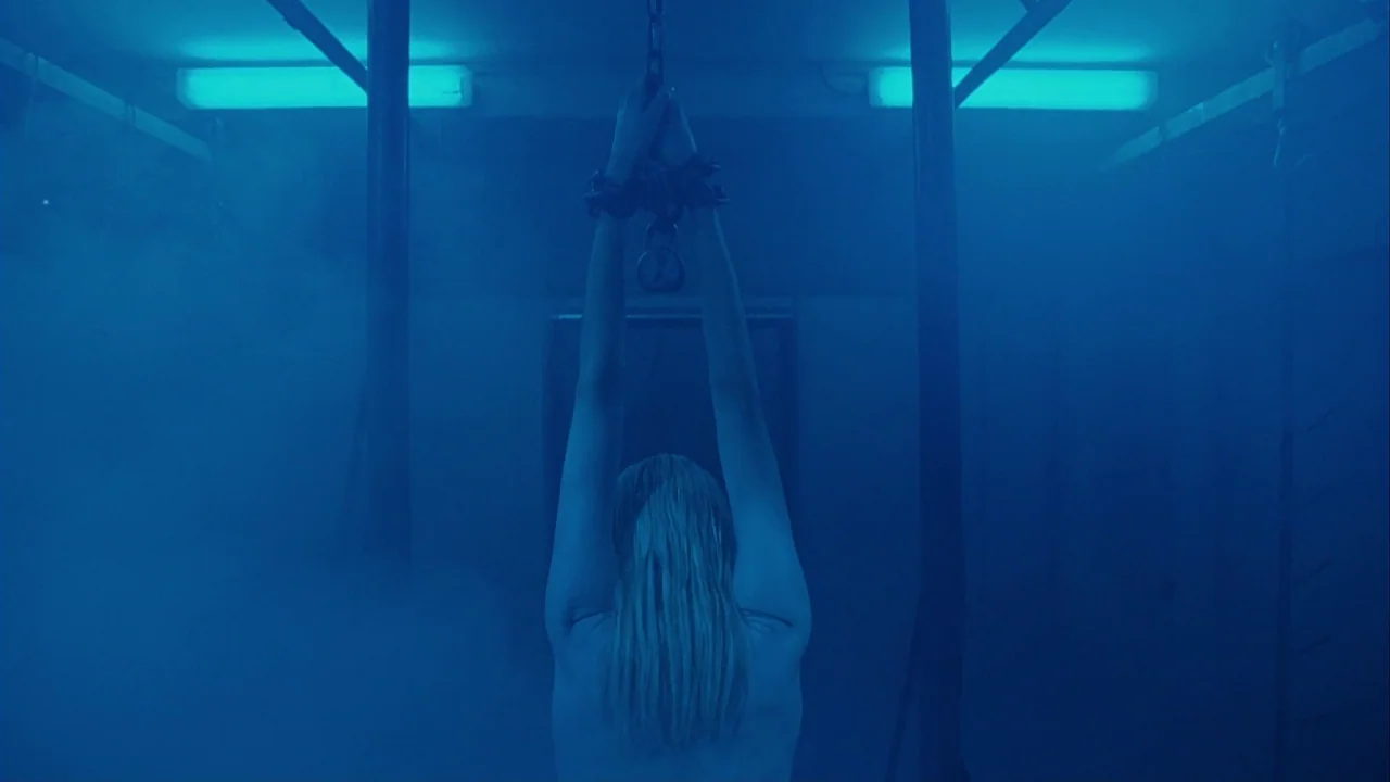 Saw III (2006) movie still: medium — An industrial room is filled with dense blue smoke and overhead fluorescent lights. A woman stands in the…