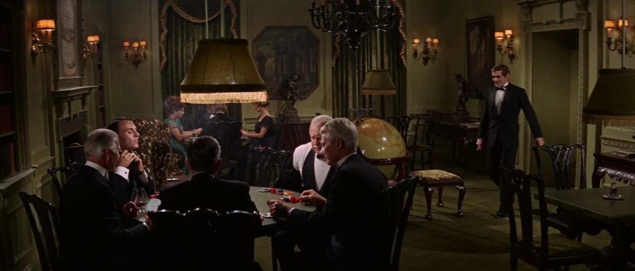 Funny Girl (1968) movie still: wide — A dark, wood-paneled club room with green carpeting and heavy velvet green curtains. Several men play poker at…