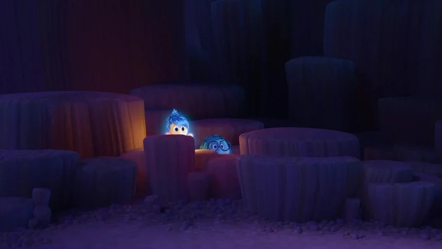 Inside Out (2015) movie still: wide — A dark subterranean space filled with clusters of smooth cylindrical stone pillars. Two small glowing…