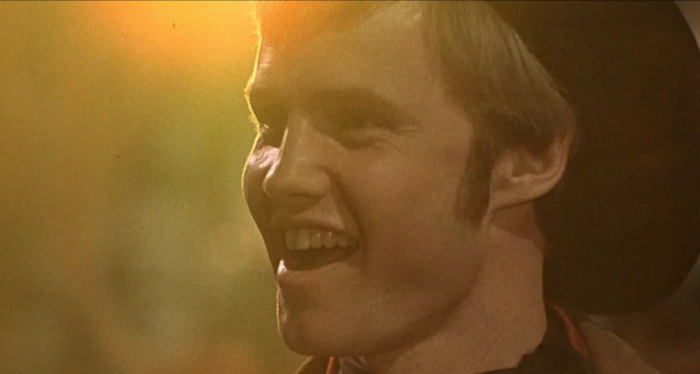 Midnight Cowboy (1969) movie still: closeup — An outdoor setting during golden hour with warm backlight on the subject. A young man with light brown…