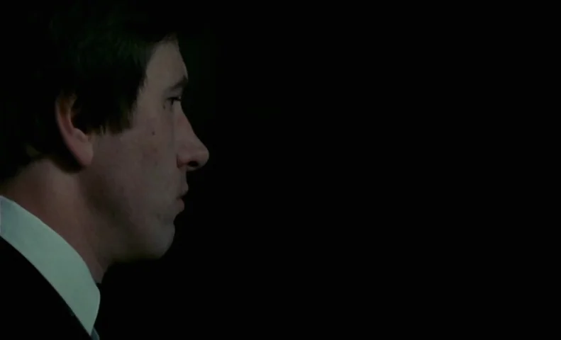 No End (1985) movie still: closeup — A man's profile is visible against a completely black background. He is turned to the right with his face…