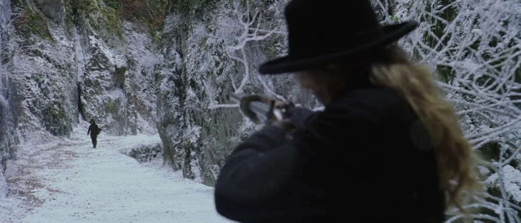 Cold Mountain (2003) movie still: wide — A snowy, narrow mountain pass with steep, frost-covered rock walls on both sides. A person with a rifle…