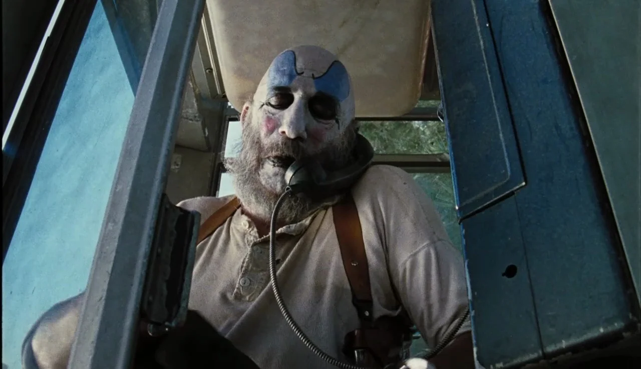 The Devil’s Rejects (2005) movie still: medium — The interior of a vehicle features metal framing and structural components around the driver. A man…