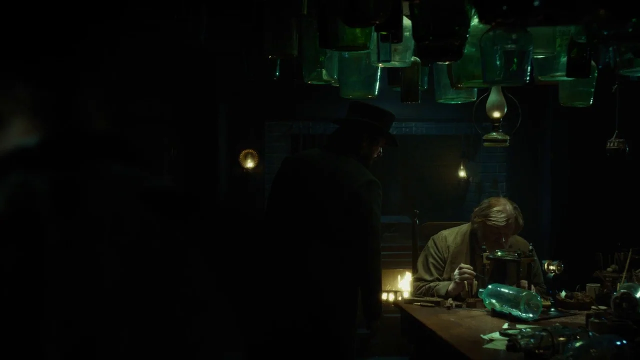In The Heart of the Sea (2014) movie still: medium — A dimly lit 19th-century workspace is filled with glass bottles suspended from the ceiling. A…
