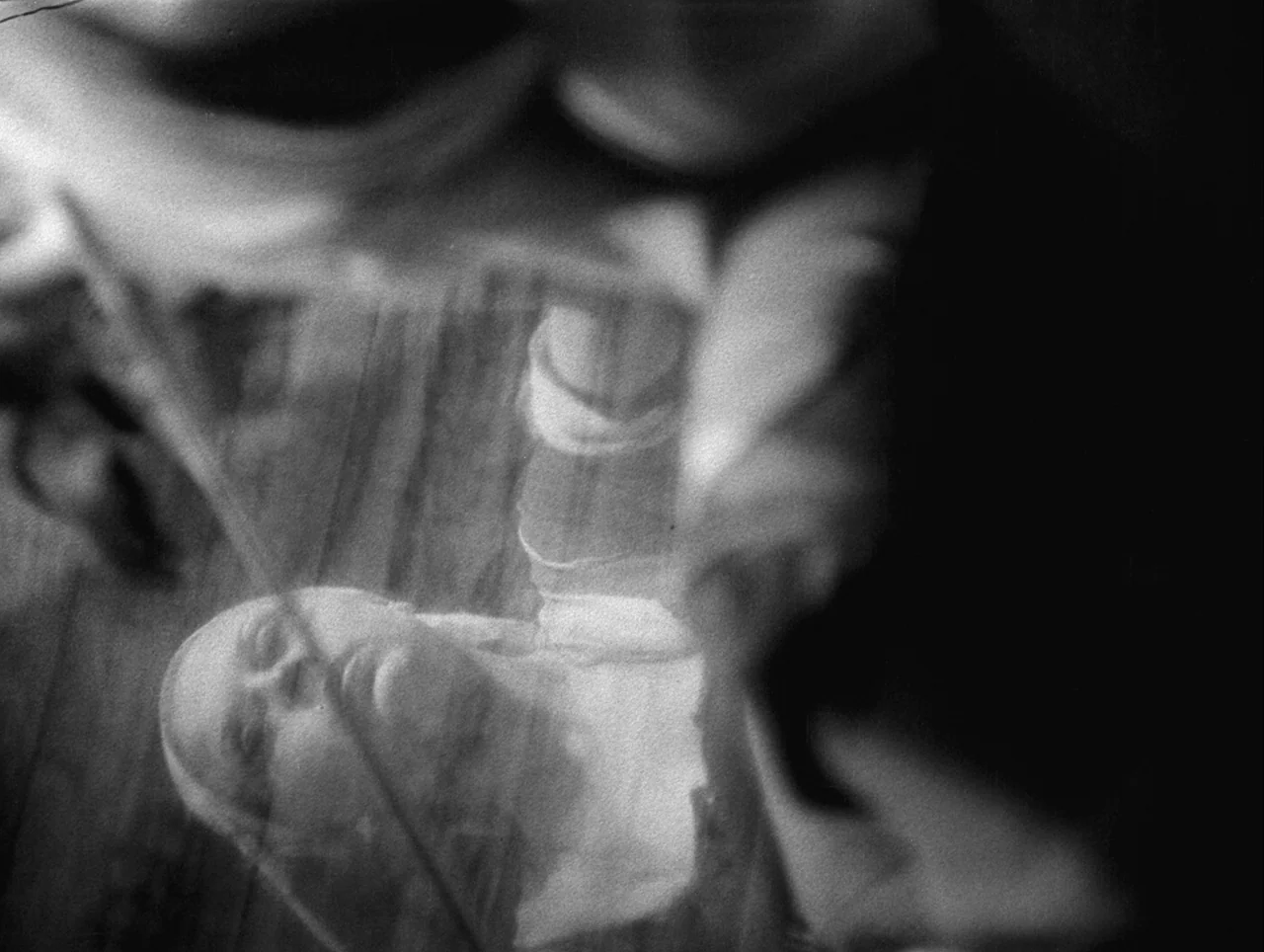 La Belle et la Bête (1946) movie still: closeup — A woman rests behind a layered, translucent veil in a darkened space. She lies horizontally with…