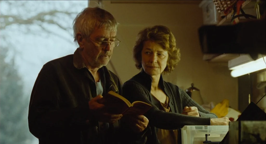 45 Years (2015) movie still: medium — A cluttered room features a window overlooking bare trees and overhead office storage racks. An older man and…