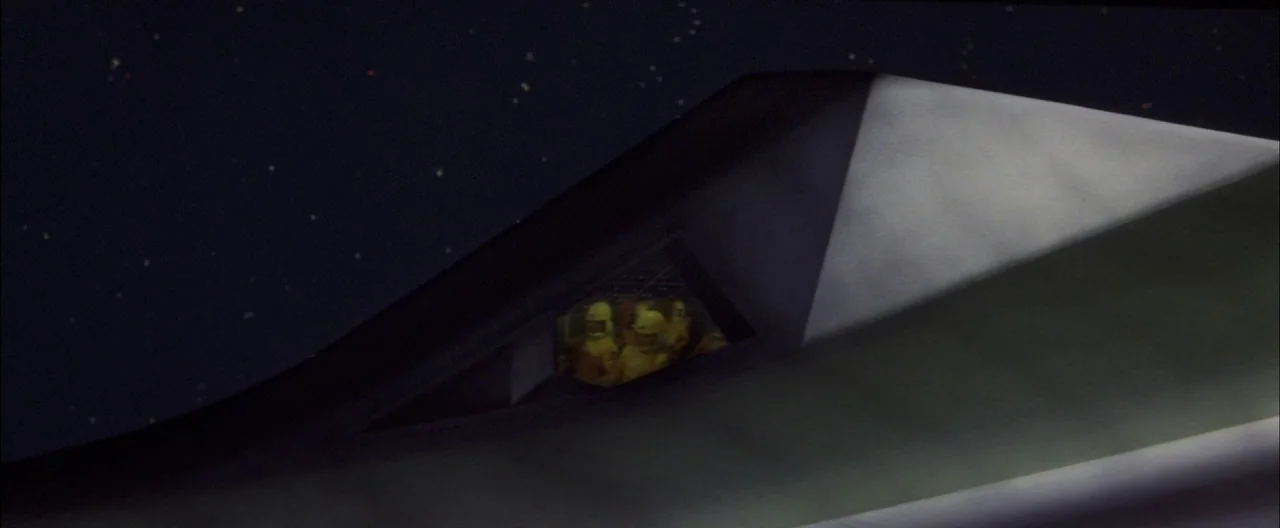 Destroy All Monsters (1968) movie still: wide — The dark, angular fuselage of a stealth fighter plane is silhouetted against a starry sky. A small,…