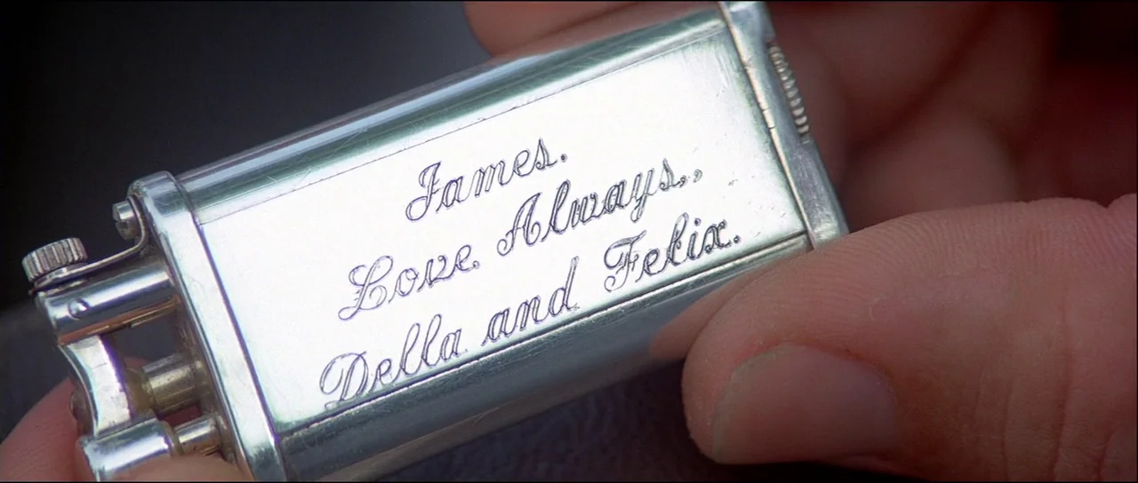 Licence to Kill (1989) movie still: closeup — A close-up shot focuses on a polished silver metal cigarette lighter being held. The inscription reads…