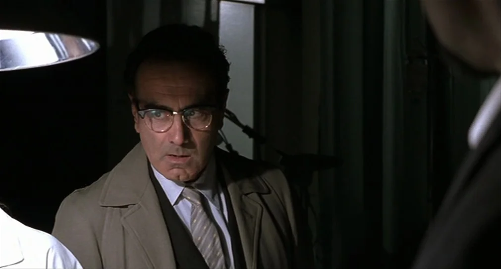 The Hurricane (1999) movie still: medium — A dark medical room contains heavy green curtains and sterile equipment in the shadows. A man wearing…