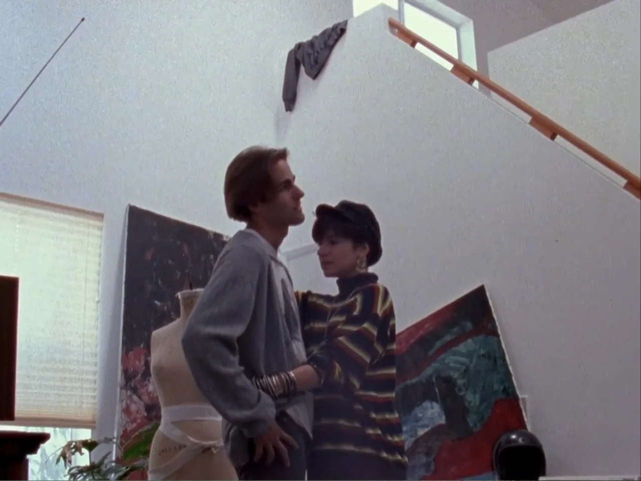 The Living End (1992) movie still: fullbody — An airy artist loft features high white walls and abstract paintings on the floor. A young man and…