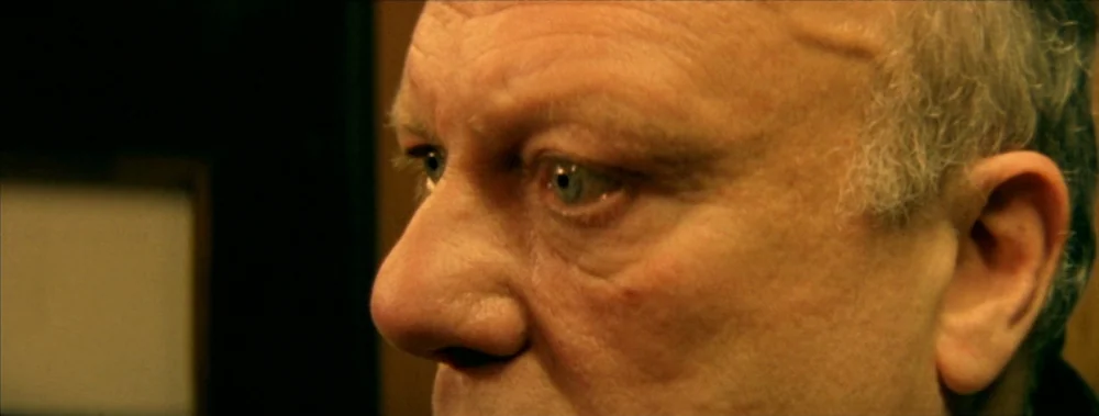 I Stand Alone (Seul Contre Tous) (1998) movie still: closeup — An interior space provides a dark background for an elderly man profile. The man…