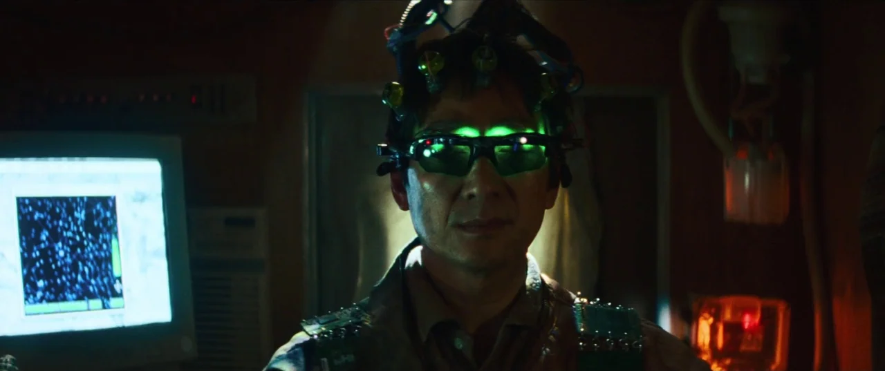 Everything Everywhere All At Once (2022) movie still: closeup — A dimly lit room contains technical equipment and glowing computer monitors. An…
