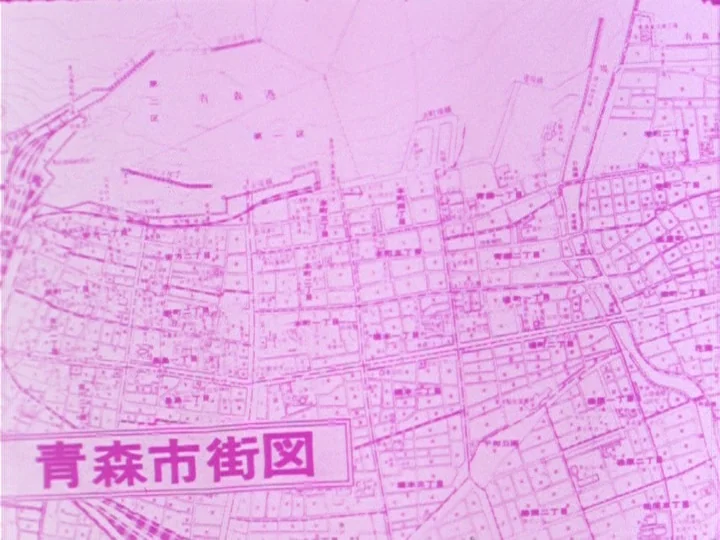Young Person’s Guide to Cinema (1974) movie still: establishing — A flat pink printed map shows the layout of Aomori city streets. Detailed grid…