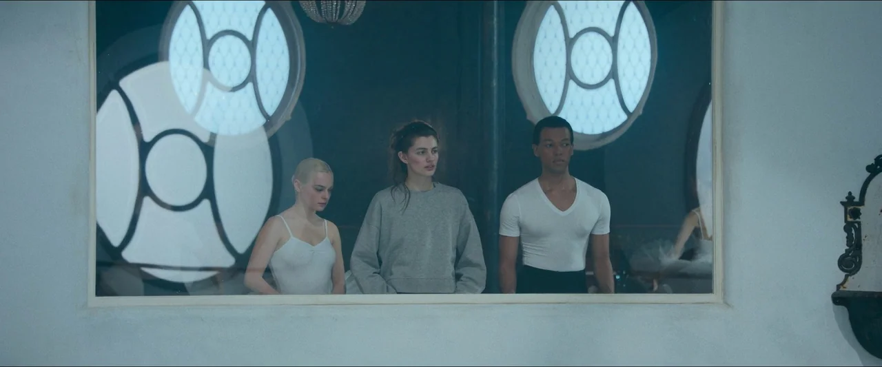 Birds of Paradise (2021) movie still: medium — A spacious studio with circular windows overlooks a darker, reflective space beyond the glass. Three…