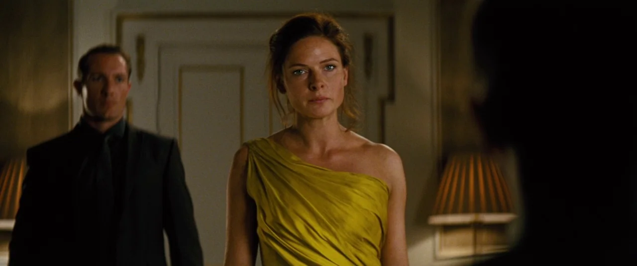 Mission: Impossible – Rogue Nation (2015) movie still: medium — A dimly lit room contains two figures centered in front of a doorway. A woman…