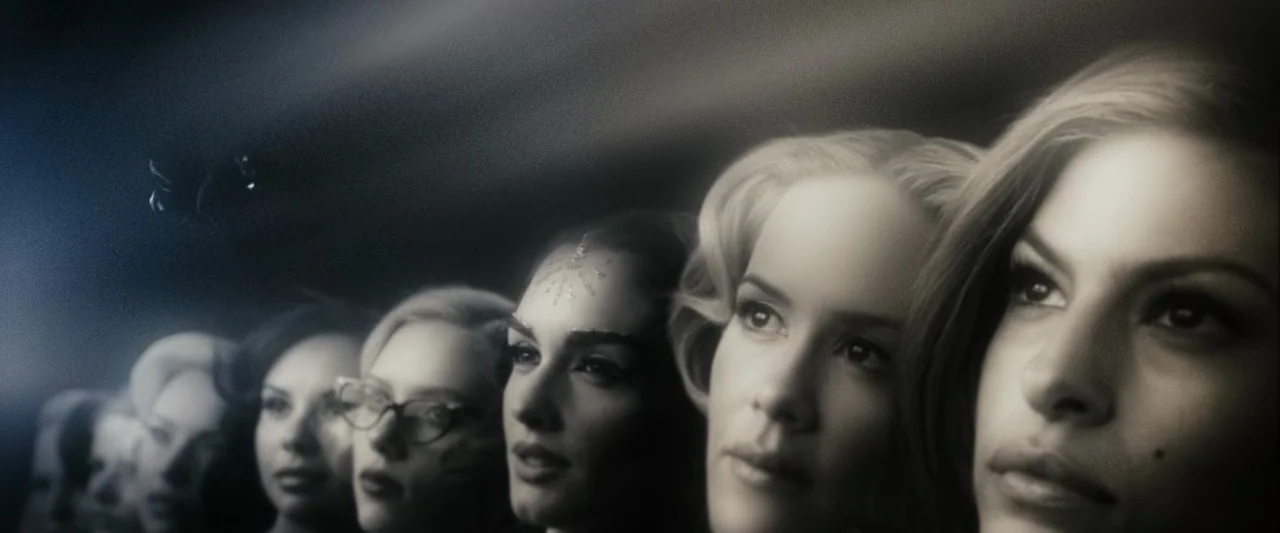 The Spirit (2008) movie still: closeup — A dark, nondescript interior space with a line of women standing side-by-side. The group gazes toward the…