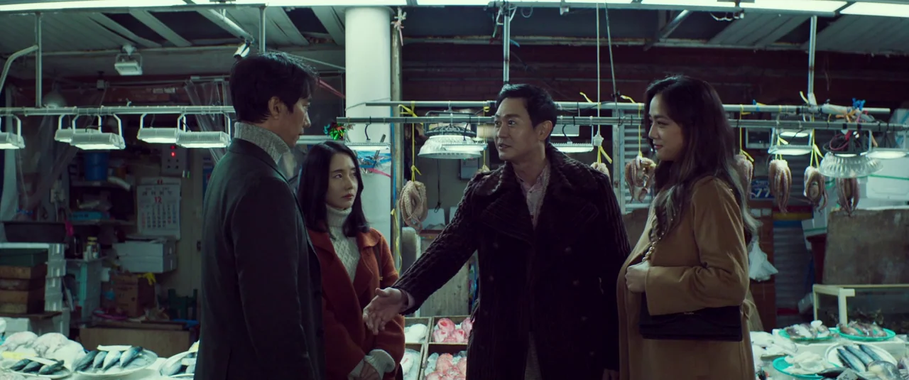 Decision To Leave (2022) movie still: medium — A fish market interior features rows of overhead fluorescent lights and crates of fresh fish. Four…