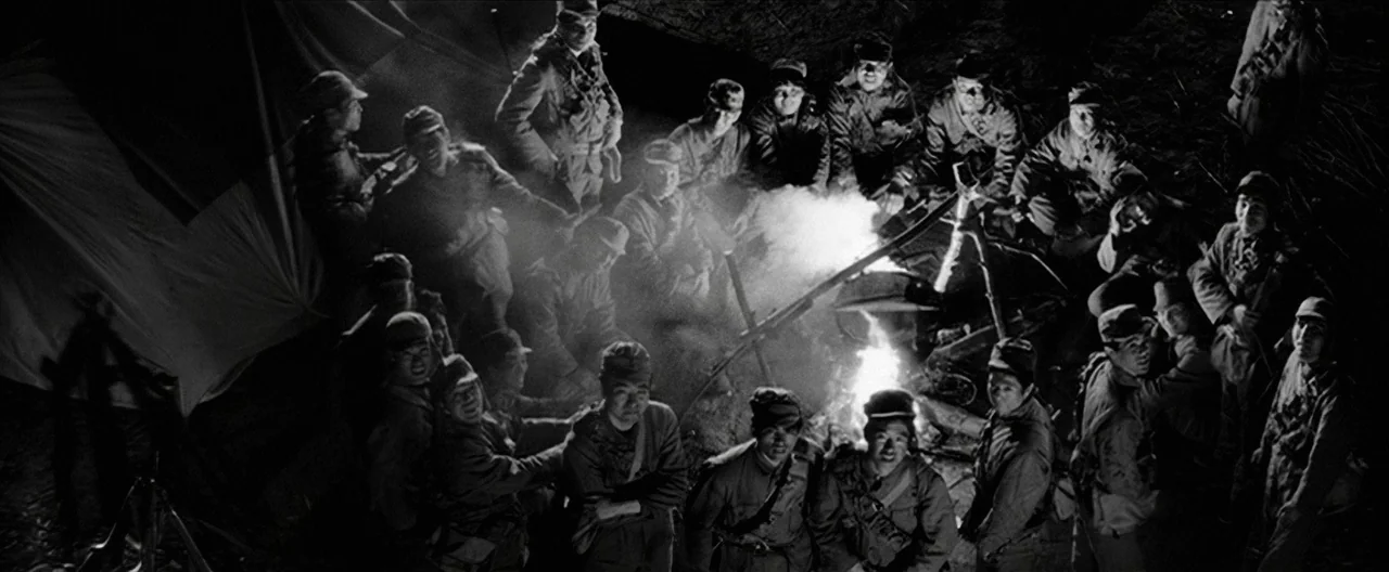 Story of a Prostitute (1965) movie still: wide — A group of soldiers sit in a circle around a burning campfire at night. They are gathered near a…