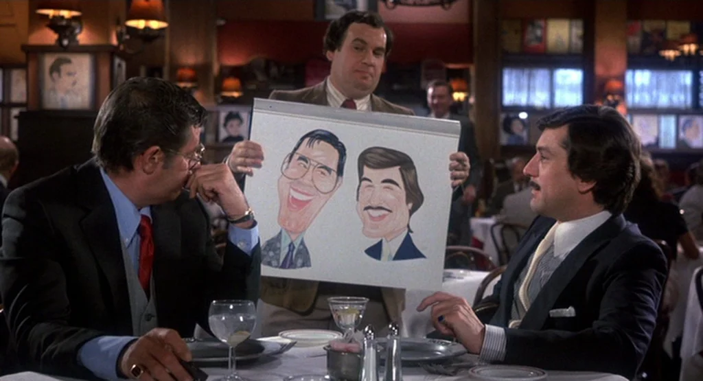 The King Of Comedy (1982) movie still: medium — A well-lit upscale restaurant features framed portraits on the walls and white-clothed dining…