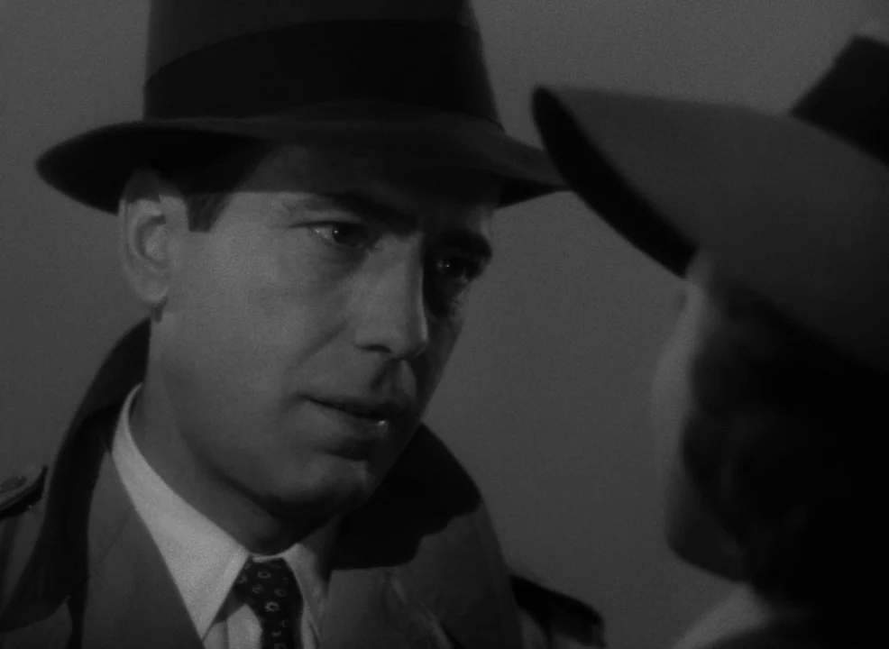 Casablanca (1942) movie still: closeup — A dark night setting with two individuals facing each other. The man is clearly visible while the woman is…