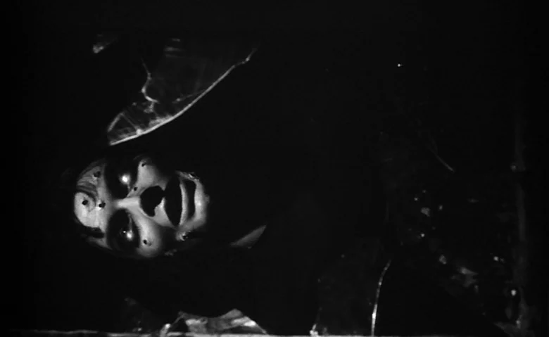Black Sunday (1960) movie still: closeup — A dark, indistinguishable space surrounds a person lying among shards of broken glass. The individual…