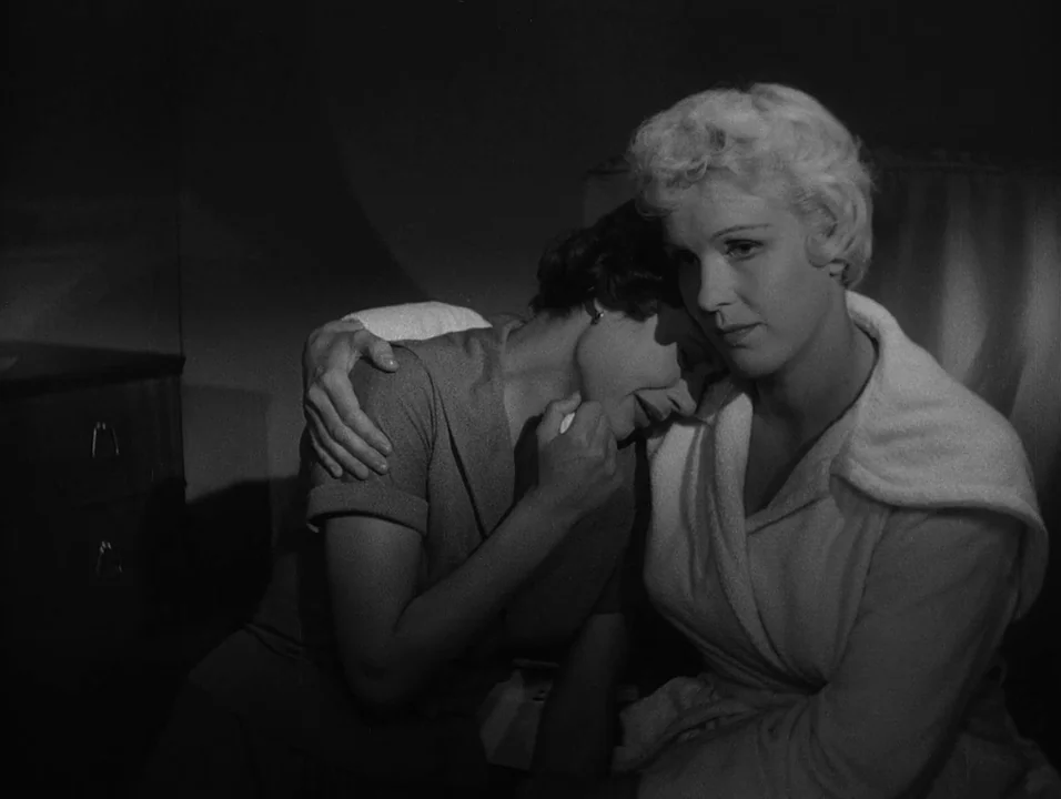 Dreams (1955) movie still: medium — A dimly lit room with shadows obscuring the walls and a visible dresser corner. Two women embrace, with one…