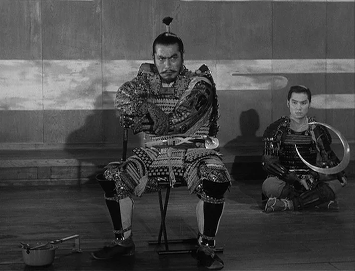 Throne of Blood (1957) movie still: fullbody — A spacious room features minimalist wooden wall panels with horizontal clouds painted across them.…