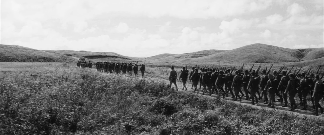 The Human Condition II: Road to Eternity (1959) movie still: wide — A vast, grassy landscape featuring rolling hills under a cloudy, bright sky. A…