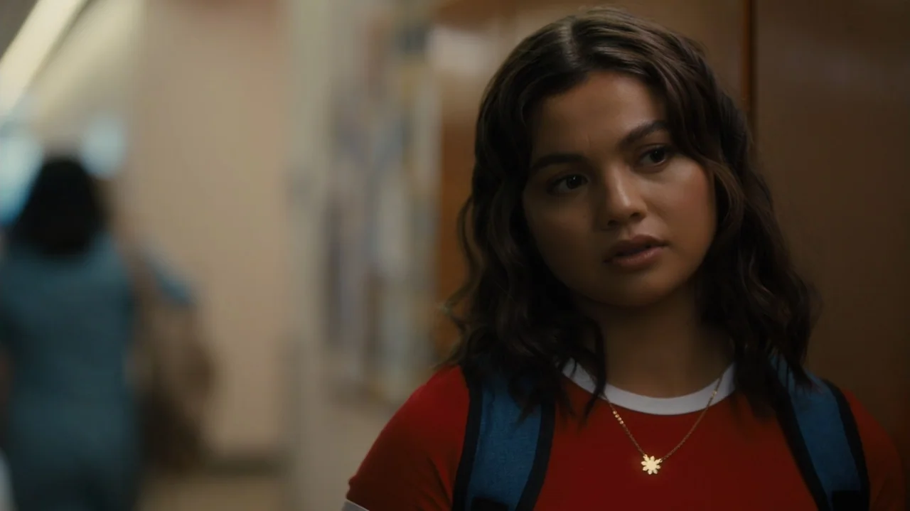 Sidelined: The QB and Me (2025) movie still: medium — A school hallway with lockers and soft, out-of-focus background activity. A teenage girl looks…