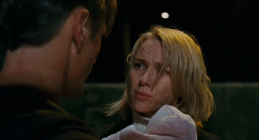 Eastern Promises (2007) movie still: closeup — A woman stands in a dark outdoor area at night holding a swaddled infant. She looks at a man whose…