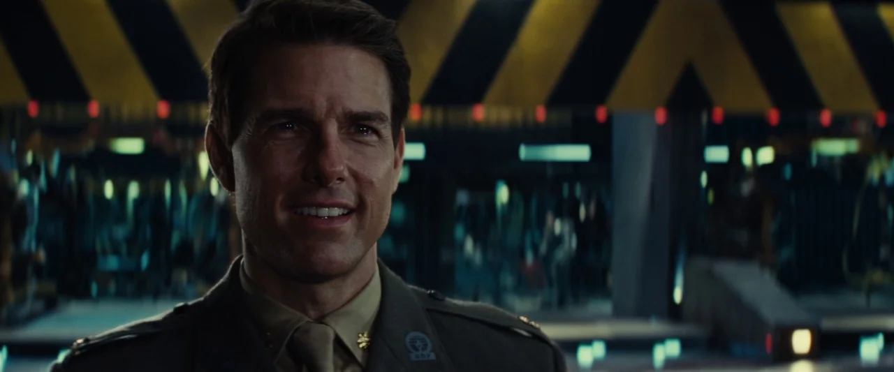 Edge of Tomorrow (2014) movie still: medium — A high-tech industrial interior features black and yellow hazard warning stripes across the ceiling. A…