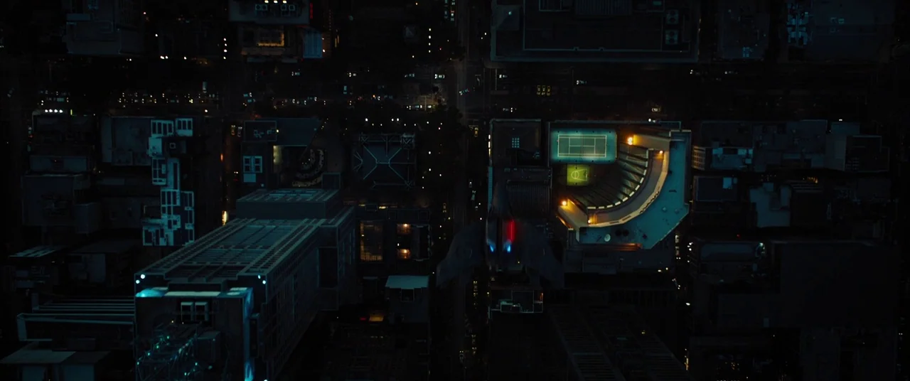 Upgrade (2018) movie still: establishing — A dense urban grid of buildings and streets is captured from directly overhead at night. A dark stealth…