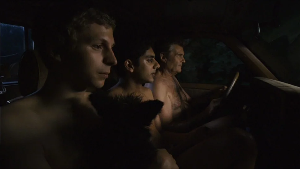 Youth In Revolt (2009) movie still: medium — The interior of a vehicle at night with three shirtless men seated together. A dark animal sits in the…