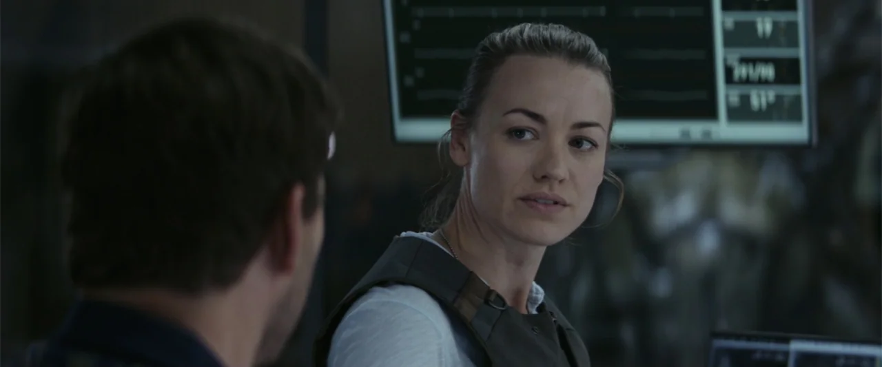 The Tomorrow War (2021) movie still: medium — A dimly lit command center features glowing medical monitors in the dark background. A woman in…