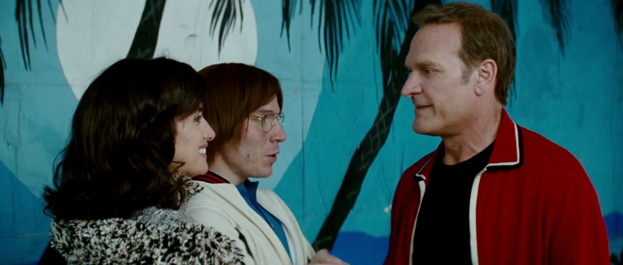 Broken Embraces (2009) movie still: medium — Three people stand before a large blue painted mural featuring stylized palm trees. The characters…