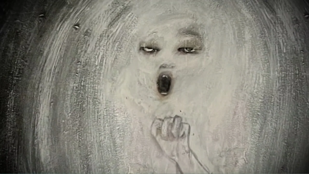 Inland Empire (2006) movie still: closeup — An abstract, textured surface features a stylized painted figure with a gaping dark mouth. A hand and…