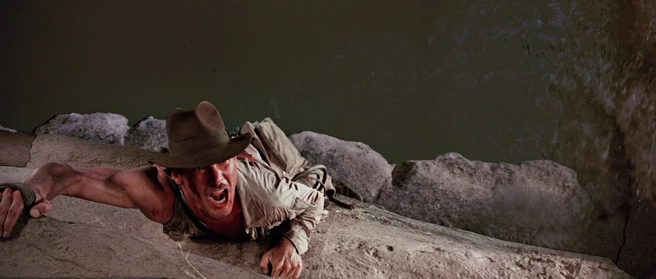 Indiana Jones and the Temple of Doom (1984) movie still: medium — A rugged stone ledge overhangs a deep, dark drop-off in a desert canyon…