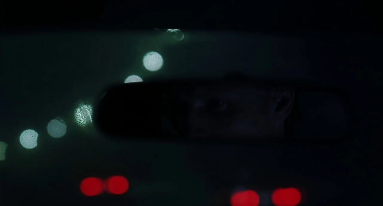 A History of Violence (2005) movie still: closeup — The interior of a car at night displays a rearview mirror in the foreground. A man's eyes and…
