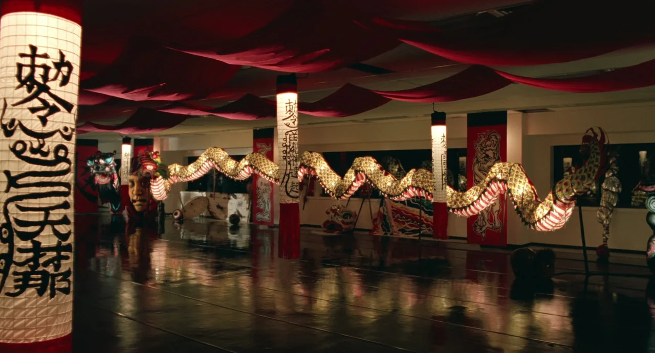 A Confucian Confusion (1994) movie still: wide — A spacious dance studio features a long, glowing dragon puppet suspended horizontally above the…