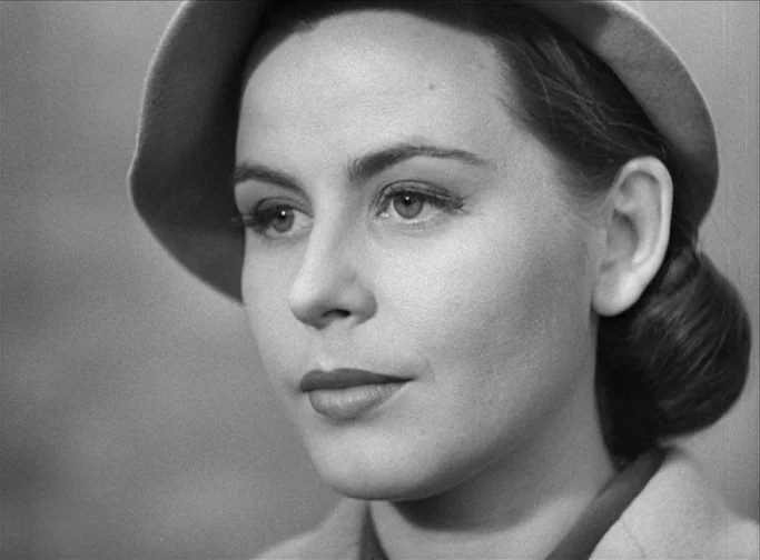 Summer Interlude (1951) movie still: closeup — A close-up view of a woman wearing a 1940s-style hat against a plain background. The woman gazes…