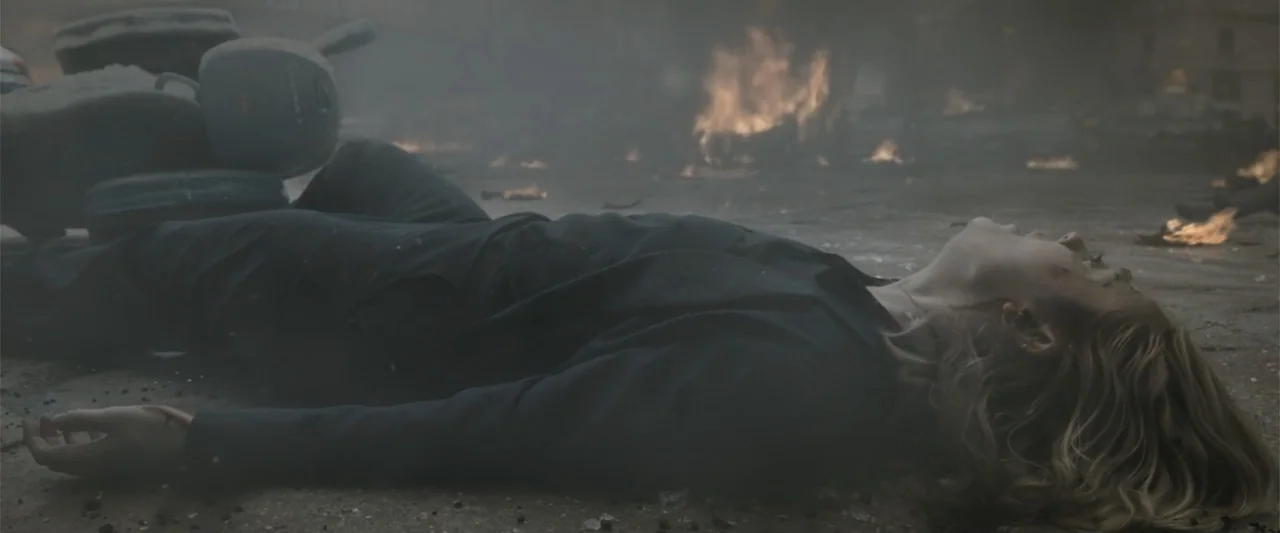 The Equalizer 3 (2023) movie still: medium — A war-torn urban street is filled with thick smoke and distant burning fires. A woman in a dark blazer…