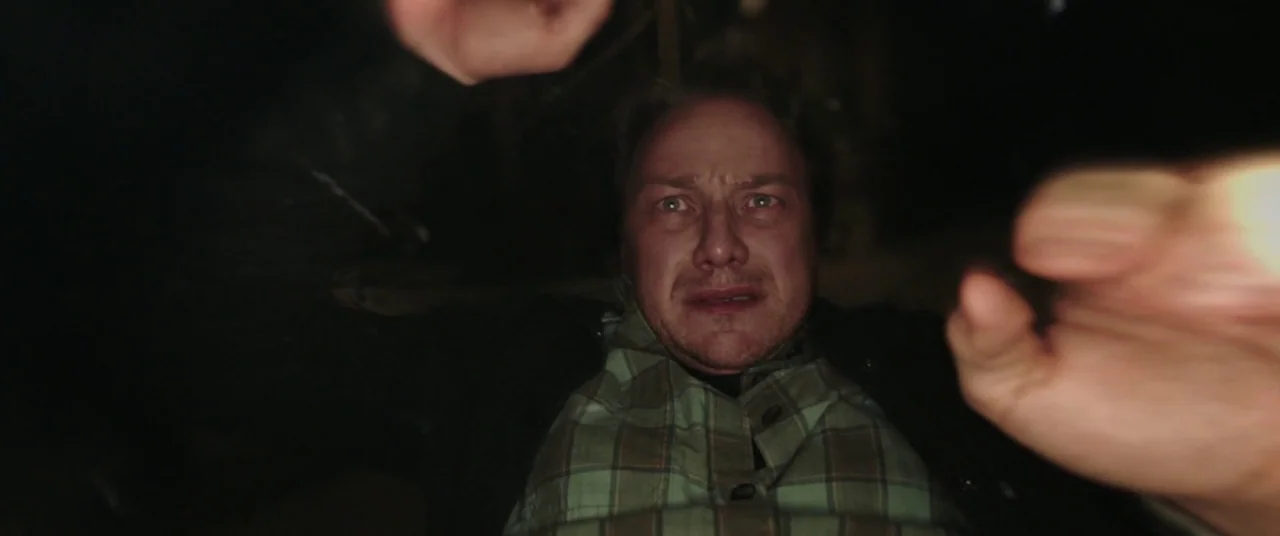 It Chapter Two (2019) movie still: closeup — A dimly lit, dark space shows a man viewed from a low angle. He looks upward with his hands reaching…