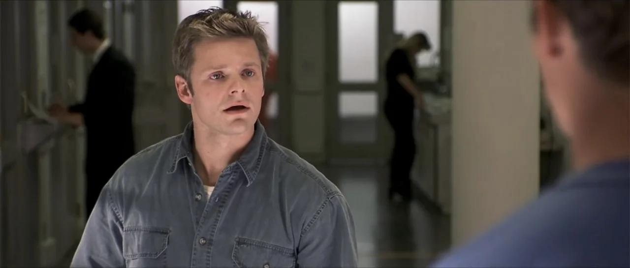 Joy Ride (2001) movie still: medium — An office hallway with white walls and glass-paned doors features blurry figures in the background. A young…