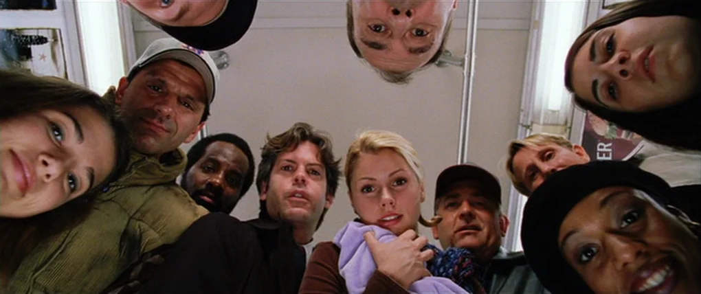 Spider-Man 2 (2004) movie still: medium — A group of diverse passengers gather together inside a brightly lit metropolitan transit car. They look…