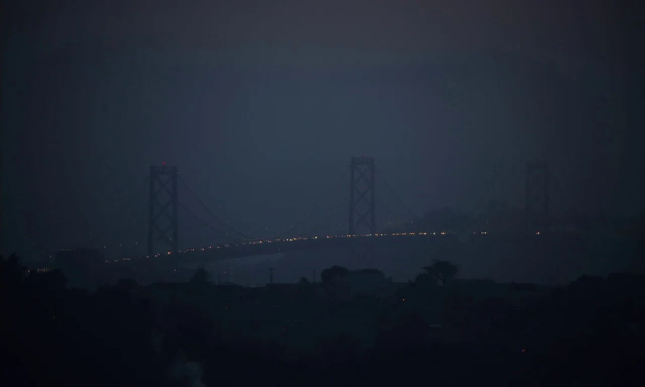 The Last Black Man in San Francisco (2019) movie still: establishing — A large suspension bridge spans across a darkened horizon under a heavy…