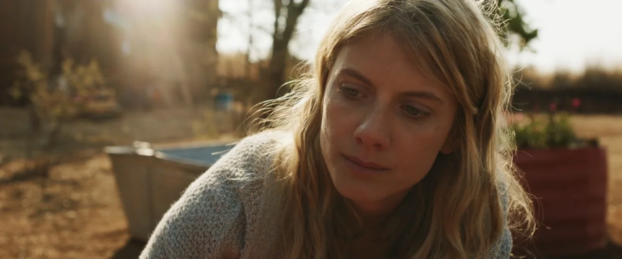 Mia and the White Lion (2018) movie still: medium — A rural backyard during golden hour with a galvanized tub and dirt ground visible. A young woman…