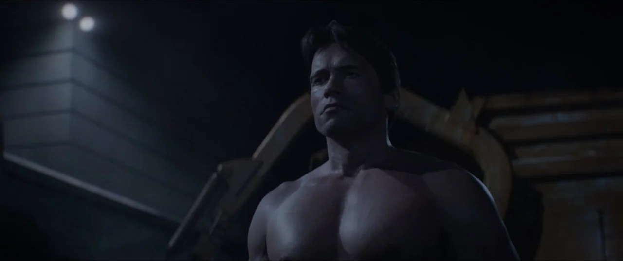 Terminator Genisys (2015) movie still: medium — An industrial facility interior features dark walls and metallic structures visible in the…